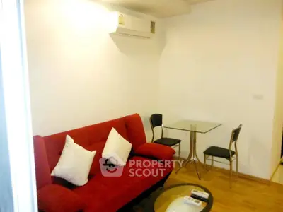 Cozy living room with red sofa and modern glass table, perfect for relaxation.