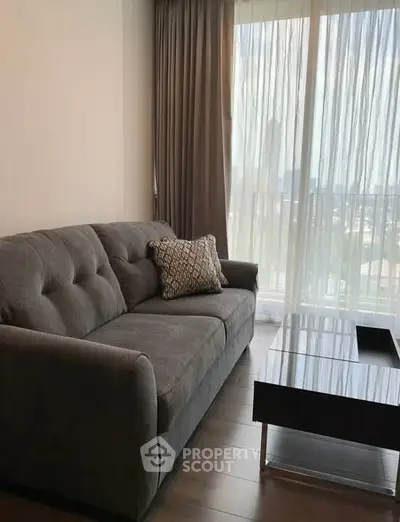 Modern living room with stylish gray sofa and large window offering natural light.