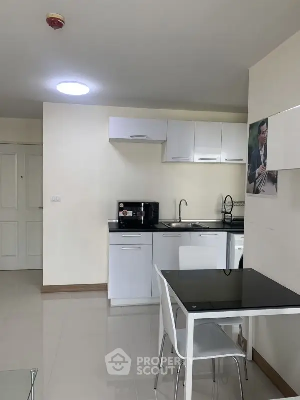 Modern compact kitchen with sleek white cabinets and dining area