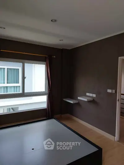 Spacious bedroom with large window and modern design elements.