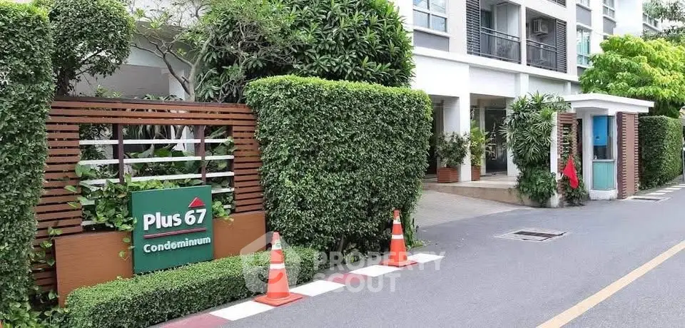 Modern condominium entrance with lush greenery and stylish signage at Plus 67.