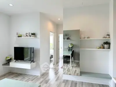 Modern living room with sleek decor and wall-mounted TV in a bright apartment.