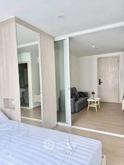 Modern bedroom with mirrored wardrobe and cozy living area in stylish apartment