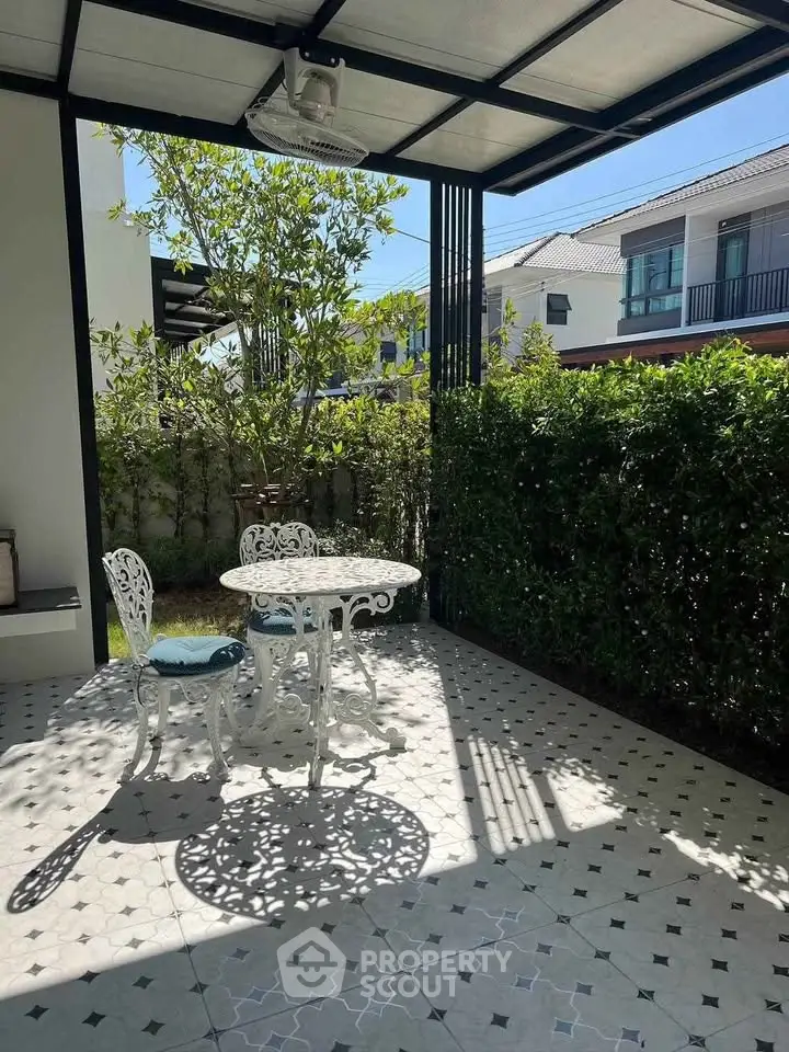 Charming garden patio with elegant white furniture and lush greenery, perfect for outdoor relaxation.