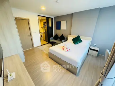 Modern bedroom with stylish decor and open view into kitchen area, featuring cozy seating and elegant design.