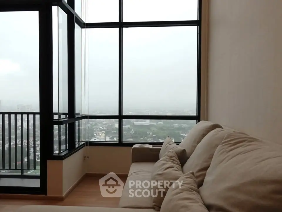 Spacious living room with large windows offering a stunning city view, perfect for relaxation.
