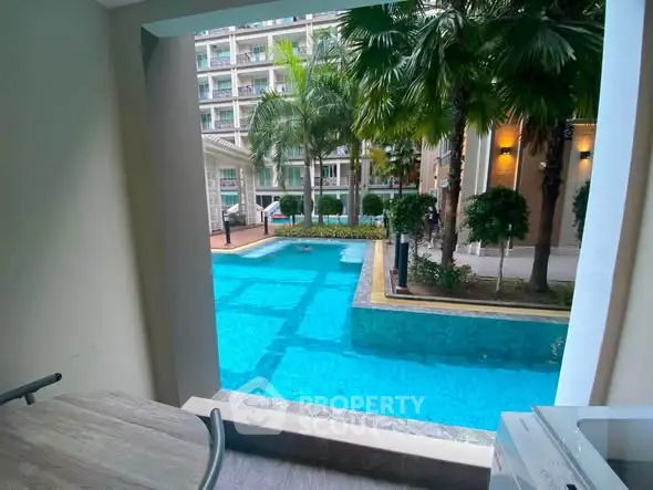Luxurious poolside view from a modern apartment balcony with lush greenery and elegant architecture.