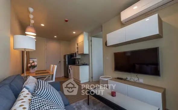 Modern living room with open kitchen, featuring stylish decor and air conditioning.