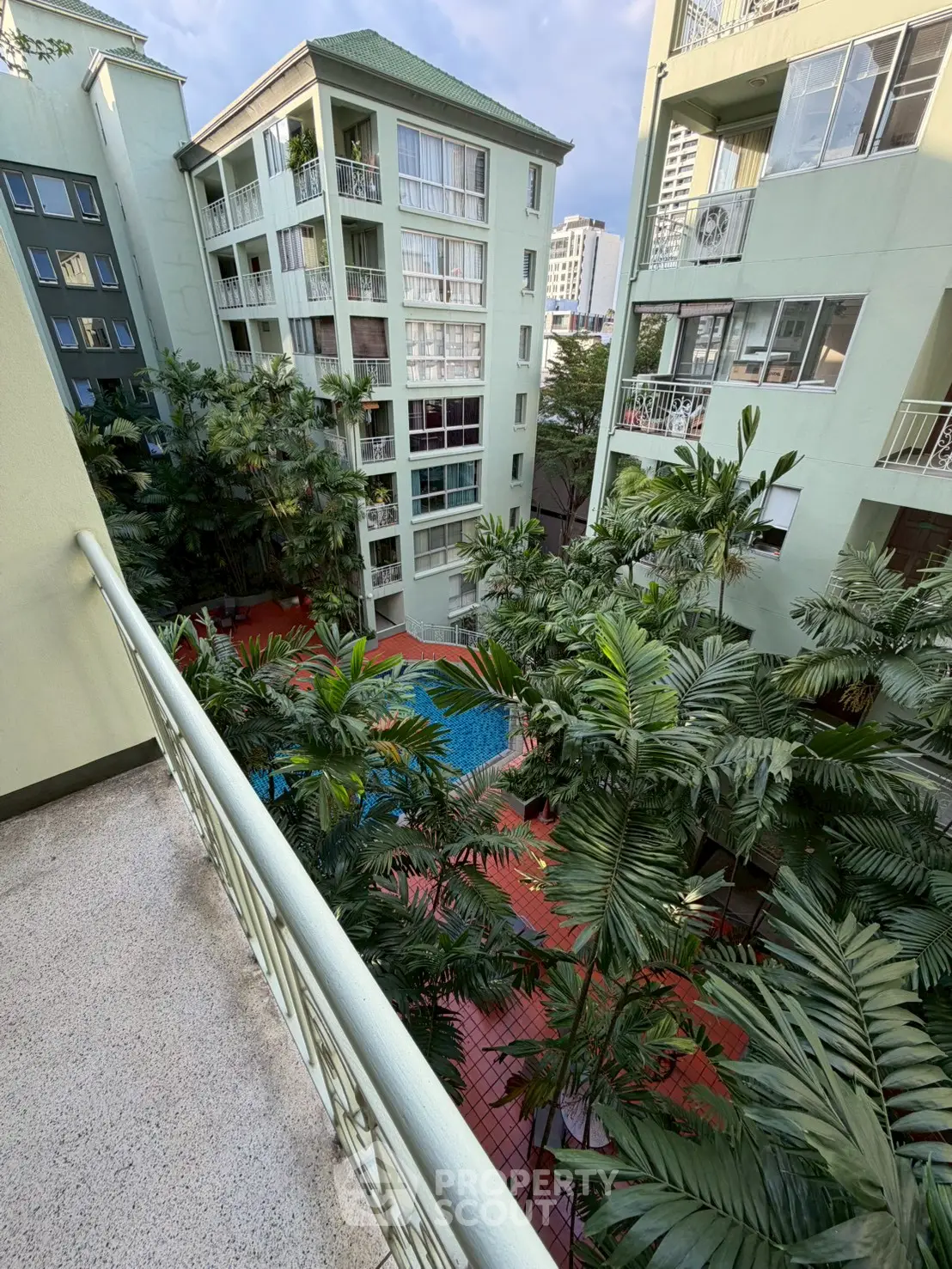 Stunning view of lush courtyard with pool in modern apartment complex.