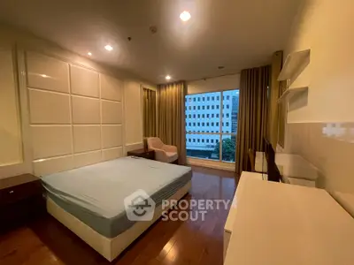 Spacious bedroom with large window and modern furnishings in urban apartment
