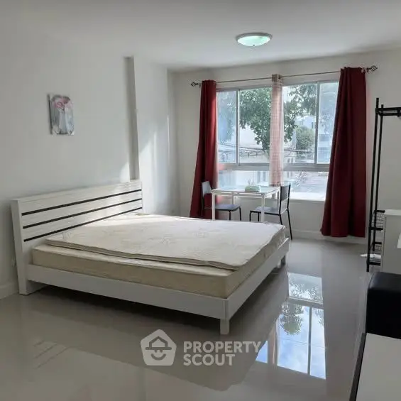Spacious bedroom with large window and modern furnishings, ideal for natural light lovers.