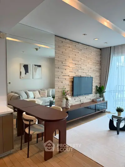 Modern living room with stylish decor and large TV, featuring a cozy seating area and elegant wooden accents.