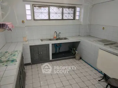 Spacious kitchen with tiled countertops and dual sink, ideal for culinary enthusiasts.