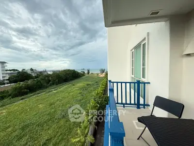 Charming balcony with scenic view of lush greenery and distant ocean, perfect for relaxation.