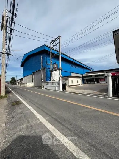 Industrial warehouse with blue exterior located on a quiet street, ideal for storage or manufacturing.