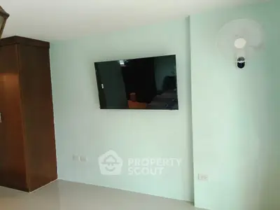Modern living room with wall-mounted TV and sleek fan, perfect for cozy relaxation.