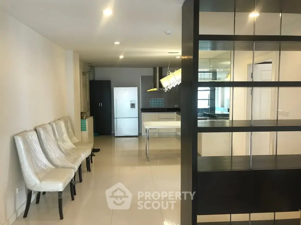Modern open-plan kitchen with sleek design and dining area, featuring contemporary chairs and bright lighting.