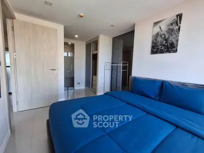 Modern bedroom with blue bedding and sleek design, featuring ample closet space and stylish decor.