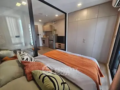 Modern studio apartment with stylish decor and open layout, featuring a cozy bed and compact kitchen area.