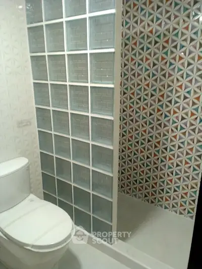 Modern bathroom with glass block partition and colorful geometric tiles