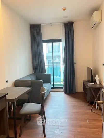 Modern living room with wooden flooring, cozy sofa, and balcony view in a stylish apartment.