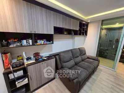 Modern living room with sleek cabinetry and cozy sofa, featuring sliding glass doors for natural light.