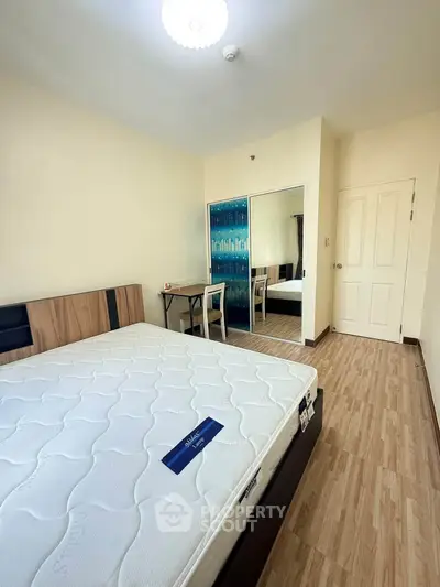 Spacious bedroom with modern furnishings and large mirror closet in a stylish apartment.