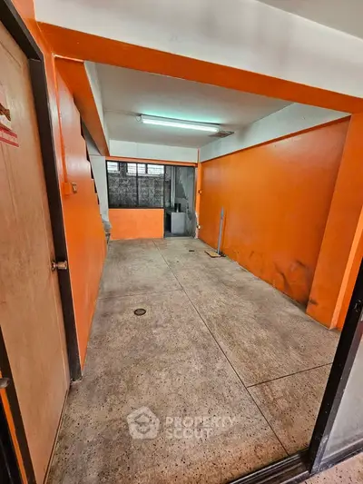Spacious garage with vibrant orange walls and concrete flooring, ideal for storage or parking.