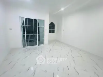 Spacious empty room with marble flooring and large windows for natural light.