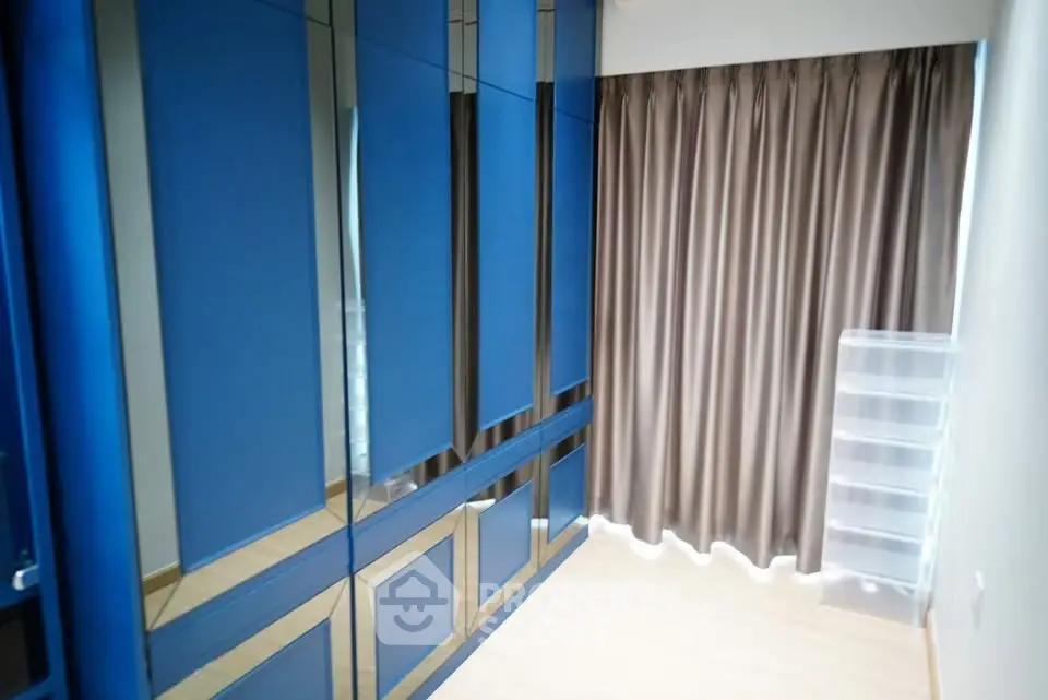 Spacious walk-in closet with sleek blue cabinetry and ample storage space.