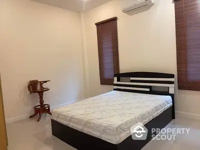 Spacious bedroom with modern bed frame, air conditioning, and elegant wooden blinds for a cozy ambiance.