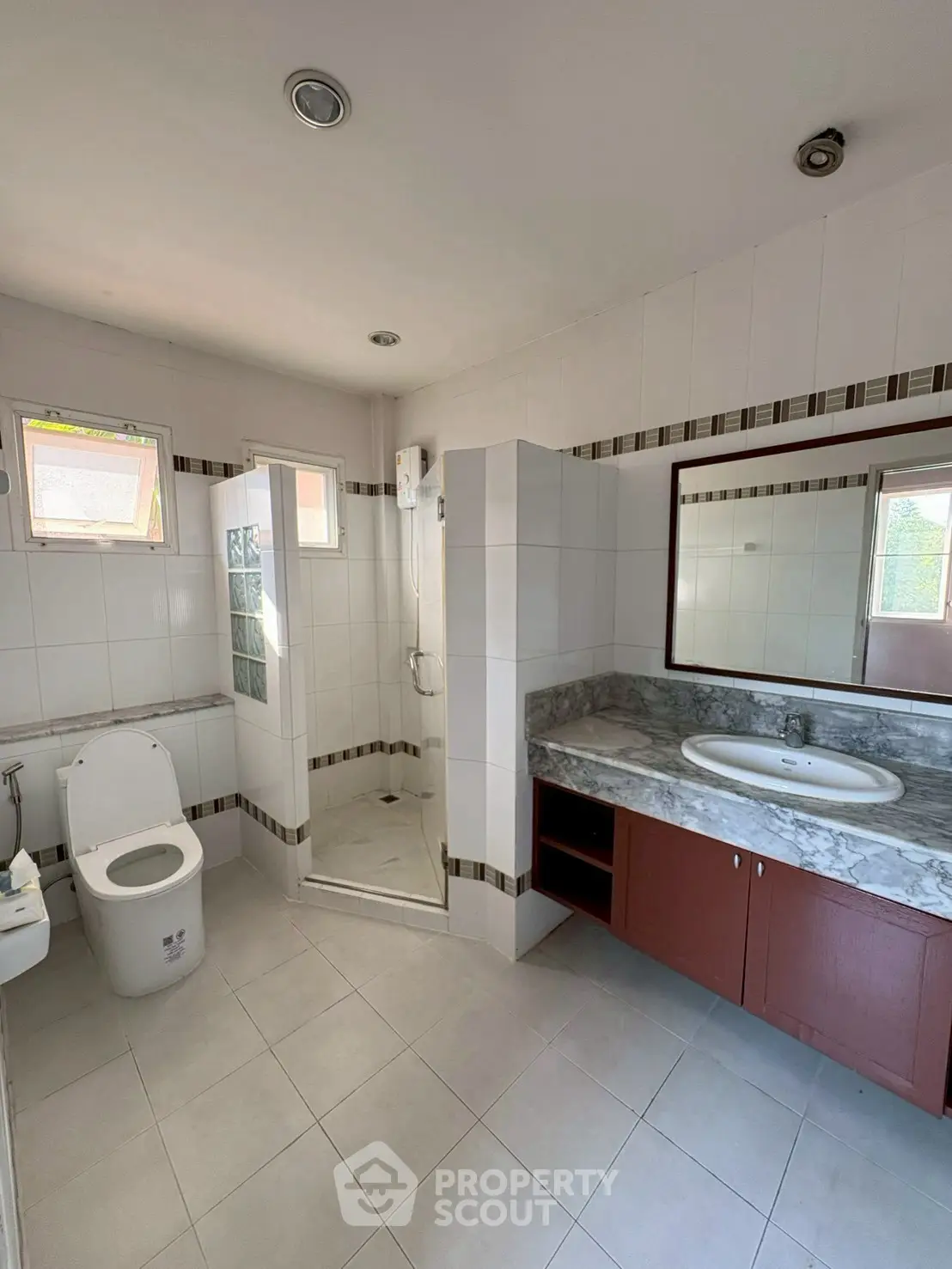 Spacious bathroom with modern fixtures and large mirror in a bright, airy setting.