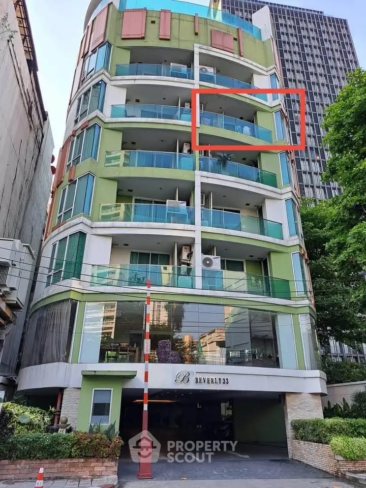 Modern multi-story building with colorful facade and glass balconies in urban setting.