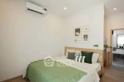 Cozy bedroom with modern decor and air conditioning, featuring a glimpse of an ensuite bathroom.
