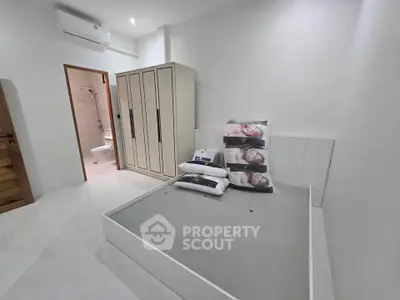 Modern minimalist bedroom with built-in wardrobe and ensuite bathroom, featuring sleek white and wood finishes.