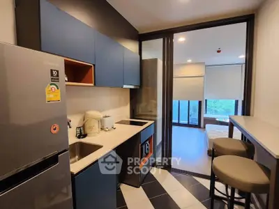 Modern kitchen with sleek cabinetry and open layout leading to a bright bedroom with large windows.