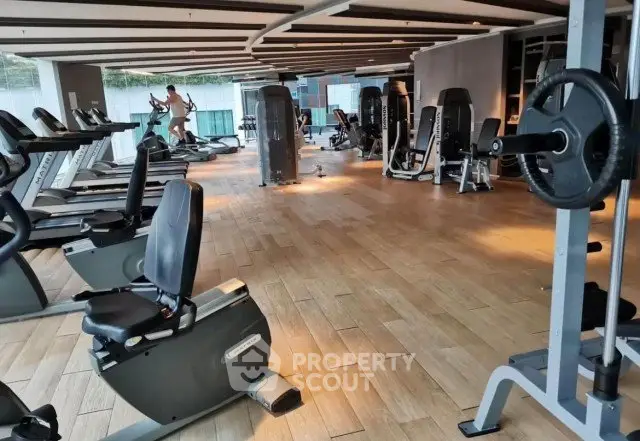 Spacious modern gym with state-of-the-art fitness equipment and wooden flooring.