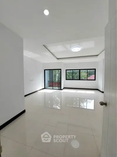 Spacious and bright living room with large windows and glossy tiled floors