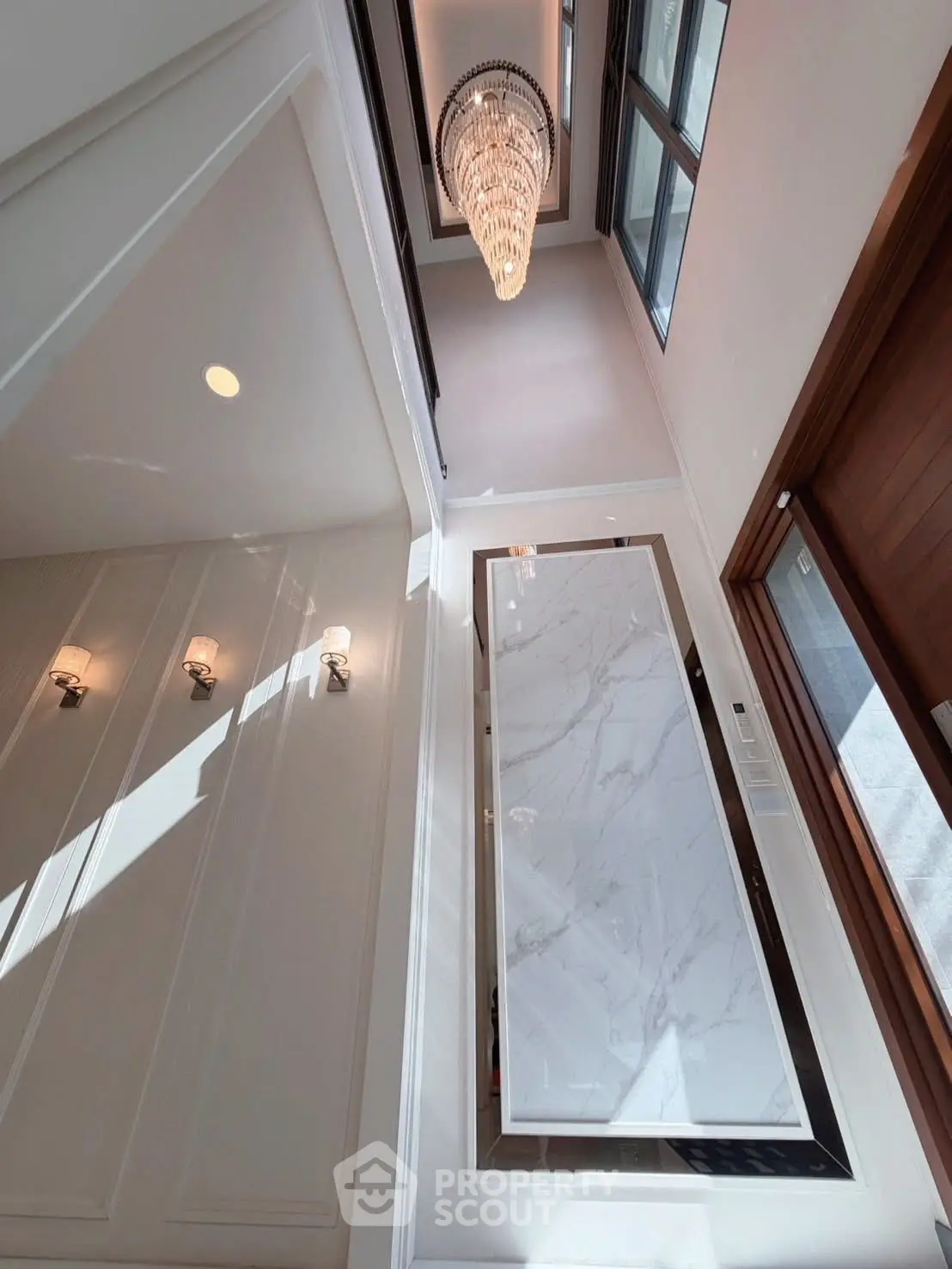 Luxurious entrance with elegant chandelier and marble accents in modern home