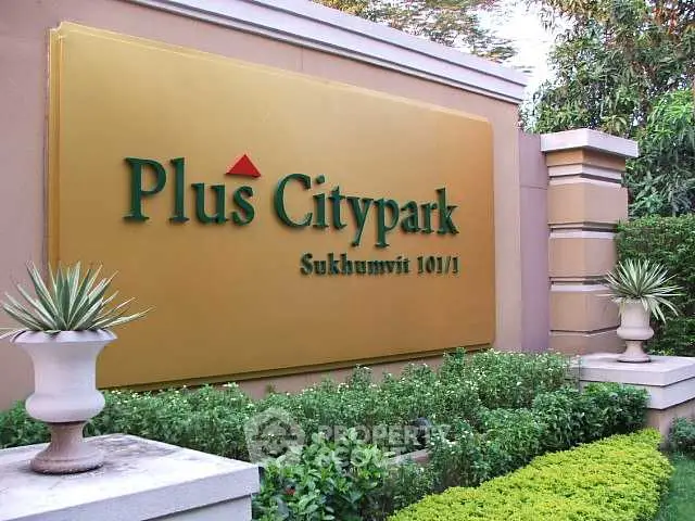 Elegant entrance sign of Plus Citypark Sukhumvit 101/1 surrounded by lush greenery.
