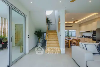 Modern open-plan living room with wooden staircase and stylish kitchen area.