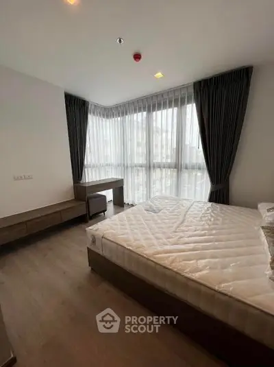 Spacious bedroom with large windows and modern furnishings in a bright apartment.