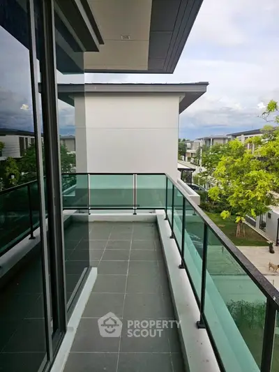 Spacious balcony with glass railing and scenic view in modern residential area.