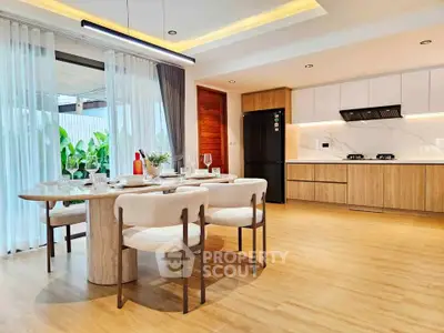 Modern open-layout kitchen and dining area with elegant wooden flooring and stylish furniture.