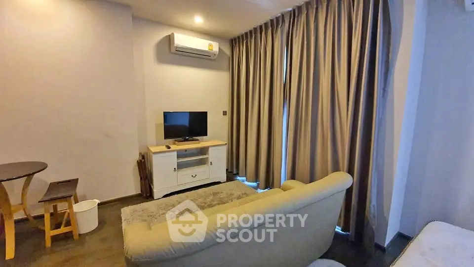 Cozy living room with modern decor, featuring a plush sofa, TV, and elegant curtains.