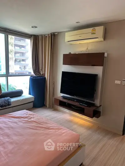 Modern bedroom with large window, TV, and air conditioning in a stylish apartment.
