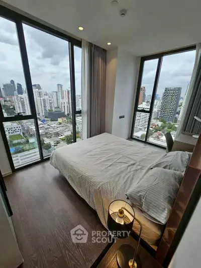 Modern bedroom with floor-to-ceiling windows offering stunning city views.