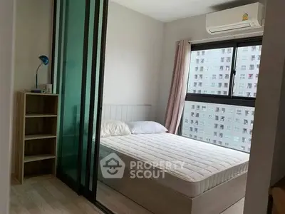 Modern bedroom with large window and air conditioning in urban apartment.