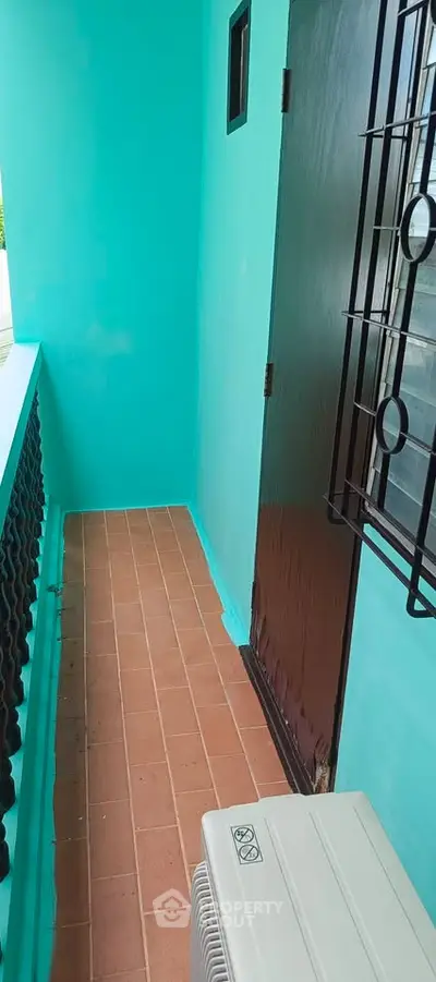 Charming balcony with vibrant turquoise walls and terracotta tiles, perfect for relaxation.