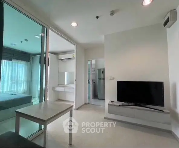Modern living room with sleek TV setup and glass partition leading to bedroom.